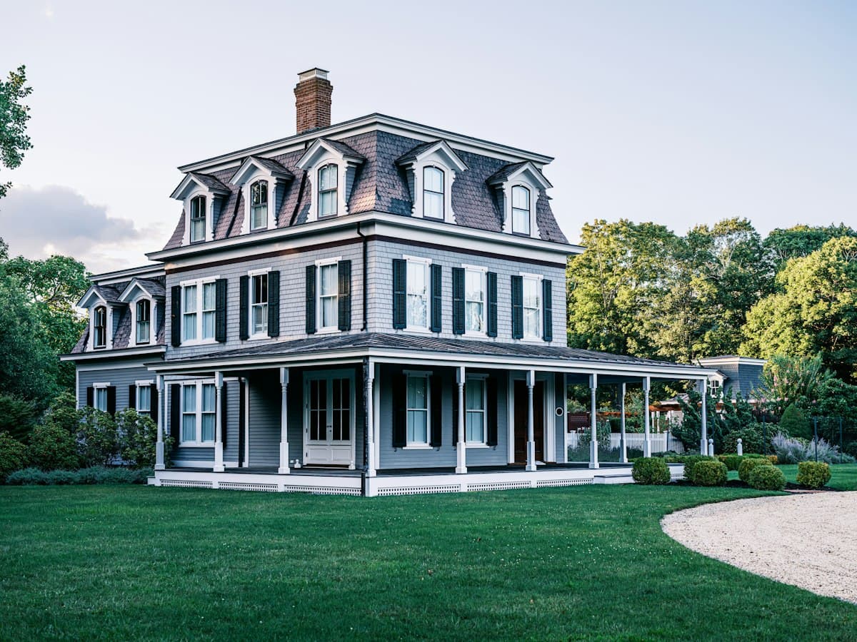 A gray Victorian home with a wraparound porch