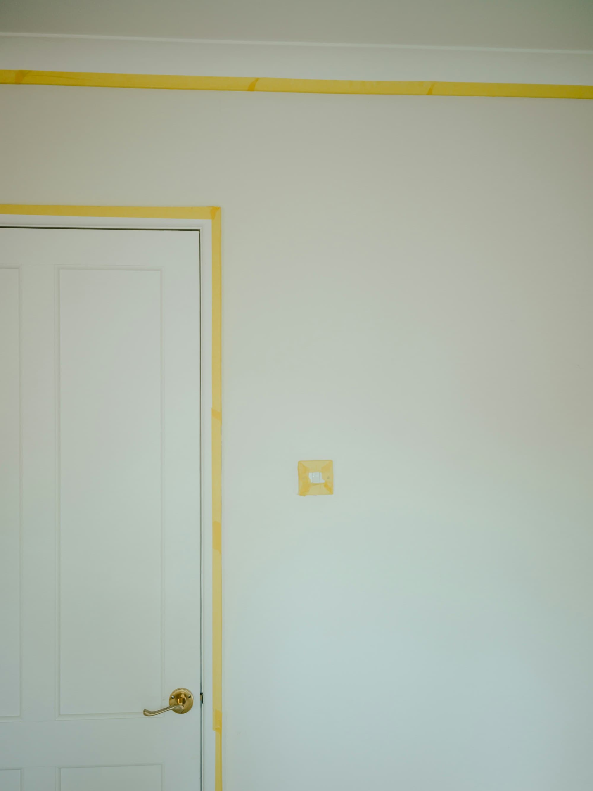 Yellow painter's tape cleanly masking a white door frame
