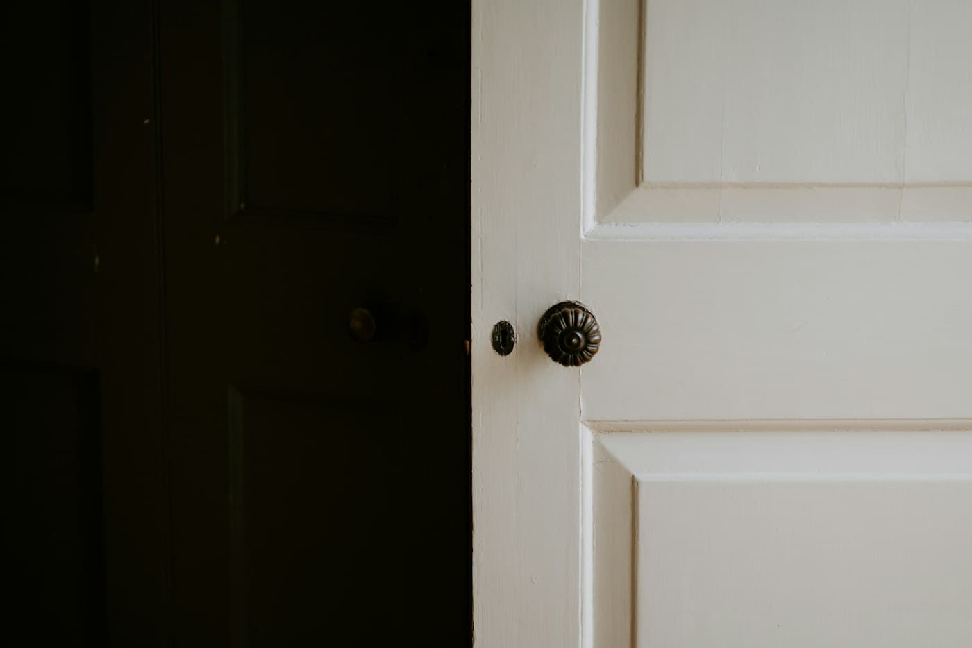 Close-up of a painted white door with a brass doorknob