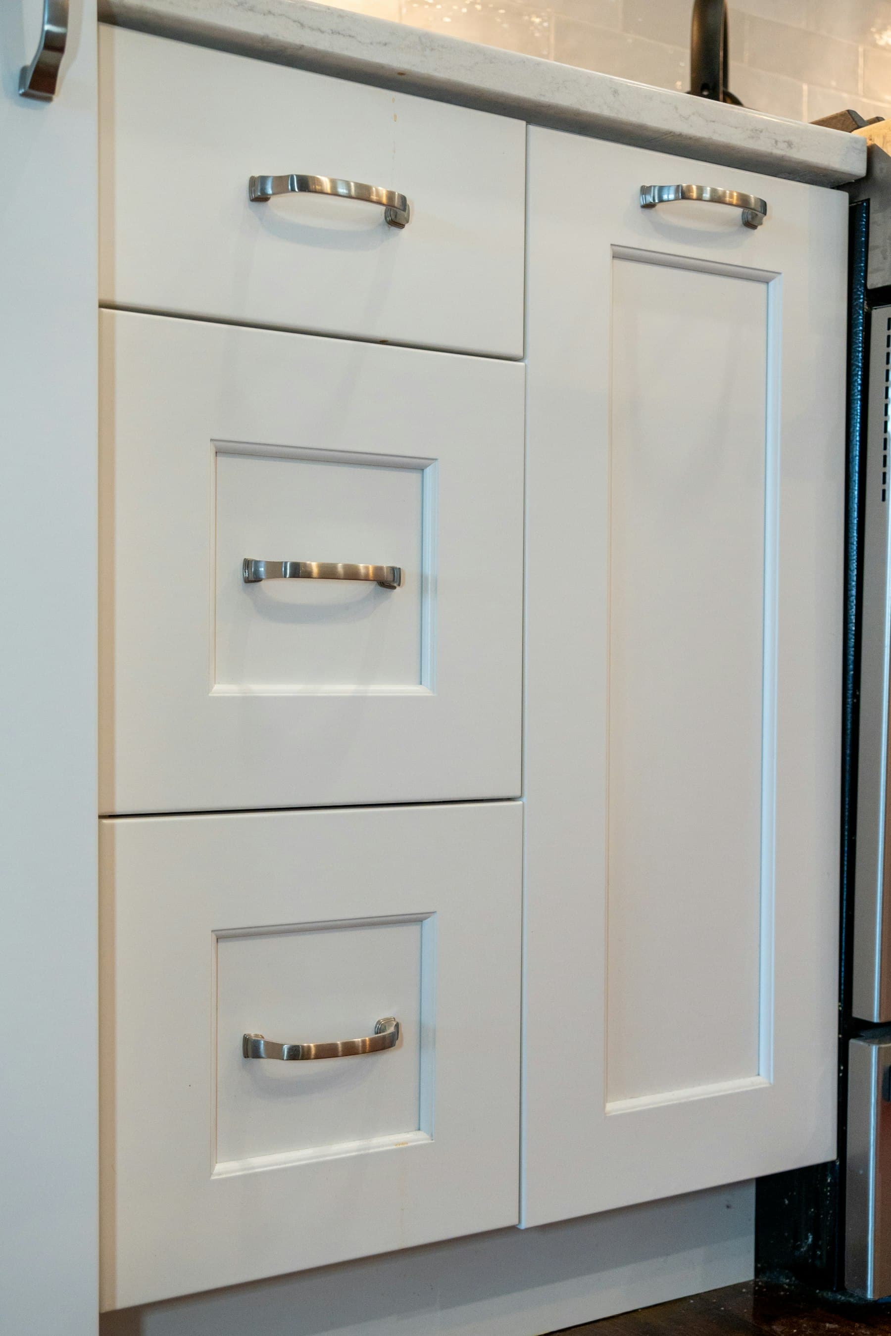 Close-up of freshly painted white shaker-style kitchen cabinets with brushed nickel hardware